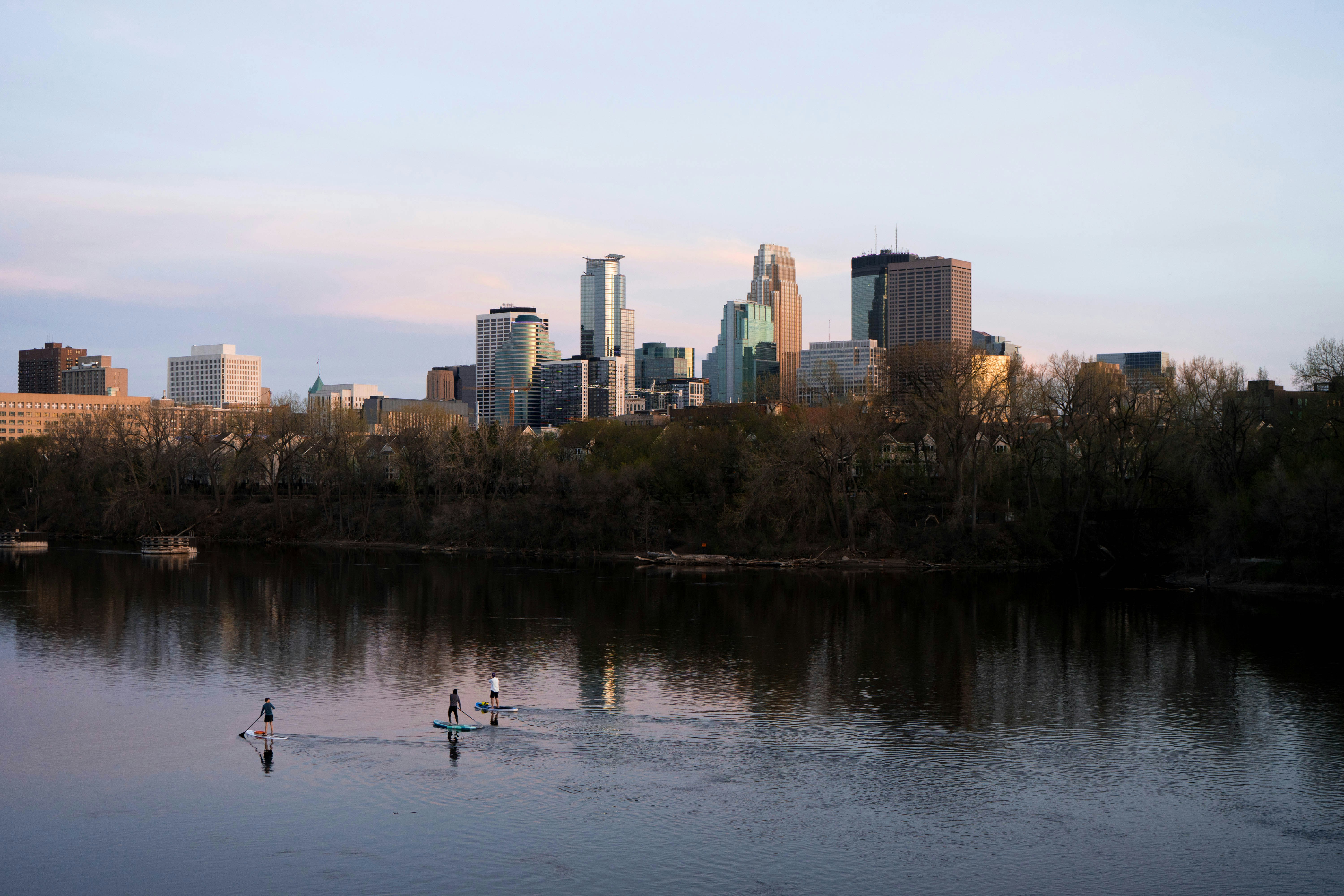 people on lake near city buildings during daytime